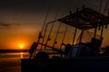 Silhouette of a fishing boat with fishing rods and reels with a golden sunset. Royalty Free Stock Photo