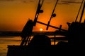 Silhouette of a fishing boat with fishing rods and reels with a golden sunset. Royalty Free Stock Photo