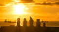 SILHOUETTE: Fishing and freight boats are anchored behind moai statues at sunset Royalty Free Stock Photo