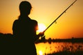 Silhouette of a fishing woman on the river bank at sunset Royalty Free Stock Photo