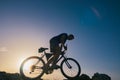 Silhouette of a fit male mountain biker riding his bike uphill on rocky harsh terrain on a sunset