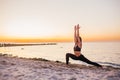 Silhouette of fitness athlete practicing warrior yoga pose meditating at beach sunset. Woman stretching doing morning meditation