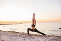 Silhouette of fitness athlete practicing warrior yoga pose meditating at beach sunset. Woman stretching doing morning meditation