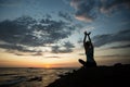 Silhouette of fitness woman doing yoga exercises on the ocean coast at twilight. Relax. Royalty Free Stock Photo