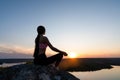 Silhouette of a fitness woman exercising yoga meditation exercises with the sun in the background Royalty Free Stock Photo