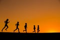 Silhouette of five running kids against sunset