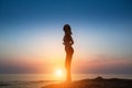 Silhouette flexible girl moves in a dance on the shore of the sea.