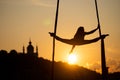 Silhouette of a flexible woman acrobat on aerial silk during a sunset on Kiev city background. concept of freedom and