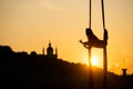 Silhouette of a flexible woman acrobat on aerial silk during a sunset on Kiev city background. concept of freedom and