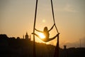 Silhouette of a flexible woman acrobat on aerial silk during a sunset on Kiev city background. concept of freedom and