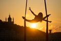 Silhouette of a flexible woman acrobat on aerial silk during a sunset on Kiev city background. concept of freedom and