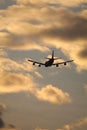 Silhouette of a flying airplane against a sunset sky with golden clouds - suitable for a wallpaper Royalty Free Stock Photo