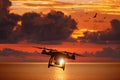 Silhouette of flying drone in glowing red sunset sky above sea Royalty Free Stock Photo