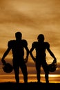 Silhouette of football players holding helmets in the sunset Royalty Free Stock Photo