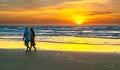 A silhouette of a foreign tourist couple happily walking together along a white sand beach Royalty Free Stock Photo