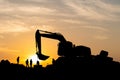 Silhouette of Foreman and workers team at construction site, Road construction worker and excavator with blurred sunset background Royalty Free Stock Photo