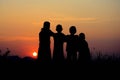 silhouette of four children standing together. There is a sky at sunset background Royalty Free Stock Photo