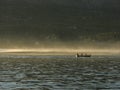 Silhouette of four men in canoe with paddles at forest background