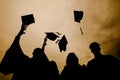 Silhouette of fresh graduates throwing their motarboard or trencher up in the air after their graduation