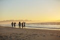 Silhouette Of Friends Having Fun Running Along Winter Beach