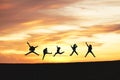 Silhouette of friends jumping in sunset and clouds on hill with copy space, business