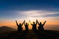 Silhouette of friends shake hands up and sitting together in sun