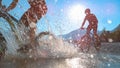 SILHOUETTE: Friends spraying water at camera while riding bicycles in Soca river Royalty Free Stock Photo