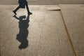 Silhouette of a girl on the background of a city street. A large shadow of a woman walking with a bag. A woman in a hurry on their