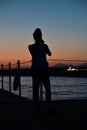 Silhouette of a girl on the background of the sea and sunset. The girl stands on the pier