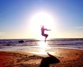 Silhouette of a girl on the background of the sun disk in a jump on the sandy seashore Royalty Free Stock Photo