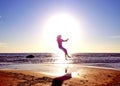 Silhouette of a girl on the background of the sun disk in a jump on the sandy seashore Royalty Free Stock Photo