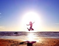 Silhouette of a girl on the background of the sun disk in a jump on the sandy seashore Royalty Free Stock Photo