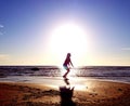 Silhouette of a girl on the background of the sun disk in a jump on the sandy seashore Royalty Free Stock Photo