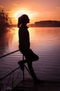 Silhouette girl background sun. Girl standing near water outdoors. Gold sunset lake. Young woman thinking about something river du Royalty Free Stock Photo