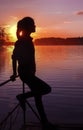 Silhouette girl background sun. Girl standing near water outdoors. Gold sunset lake. Young woman thinking about something river du Royalty Free Stock Photo
