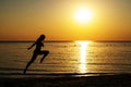 Silhouette of a girl in a bathing suit running along the beach on the background of the dawn Royalty Free Stock Photo