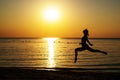 Silhouette of a girl in a bathing suit running along the beach on the background of the dawn Royalty Free Stock Photo