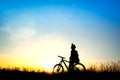 Silhouette of girl with bicycle on field during the sky sunset Royalty Free Stock Photo
