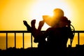 A Silhouette of a girl with a chair on a loggia balcony background. Happy woman with a hat in her arms while on vacation traveling Royalty Free Stock Photo