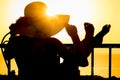 A Silhouette of a girl with a chair on a loggia balcony background. Happy woman with a hat in her arms while on vacation traveling Royalty Free Stock Photo