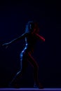 Silhouette of a girl dancing zumba. Side lit with blue and red lights on dark background Royalty Free Stock Photo