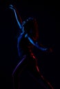 Silhouette of a girl dancing zumba. Side lit with blue and red lights on dark background Royalty Free Stock Photo