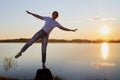 Silhouette of a girl doing sports exercises on the lake and sunset with the sun and rays in the background Royalty Free Stock Photo