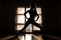 silhouette of a girl is engaged in fitness against the backdrop of the evening window sun generative ai