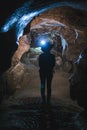 Silhouette Girl exploring huge cave. Adventure traveller dressed cowboy hat and backpack, leather jacket. vertical photo, tourist Royalty Free Stock Photo