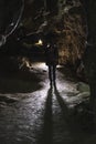 Silhouette girl exploring huge cave. Adventure traveller dressed cowboy hat and backpack, leather jacket. Vertical photo, tourist Royalty Free Stock Photo