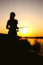Silhouette of a girl with a fishing rod on the river bank Royalty Free Stock Photo