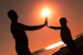 Silhouette of a girl with her father, palms of hands raised up to each other against the background of sunset the sea