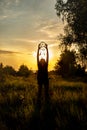 Silhouette of a girl holding an amulet high above her head. The keeper of wishes and dreams.