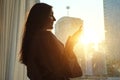 Girl in bathrobe uses phone standing near window in hotel Royalty Free Stock Photo